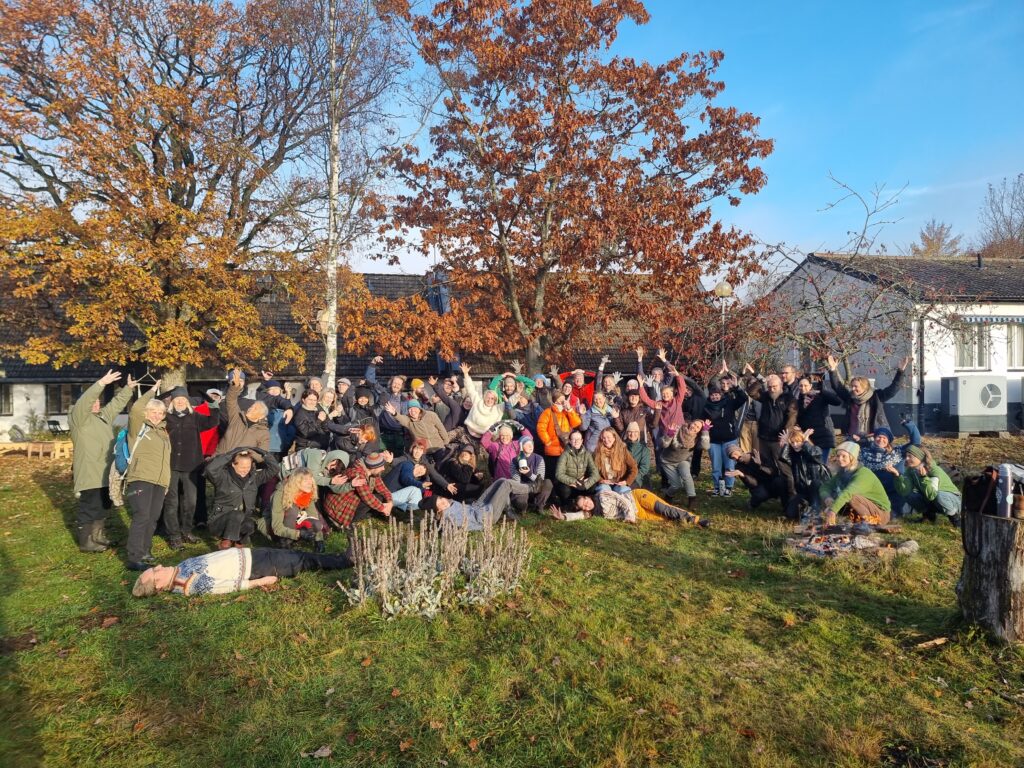 Alla deltagare på Holma har samlat sig i en grupp för ett porträtt. De står tillsammans utanför Holma Folkhögskola. Det är höst.